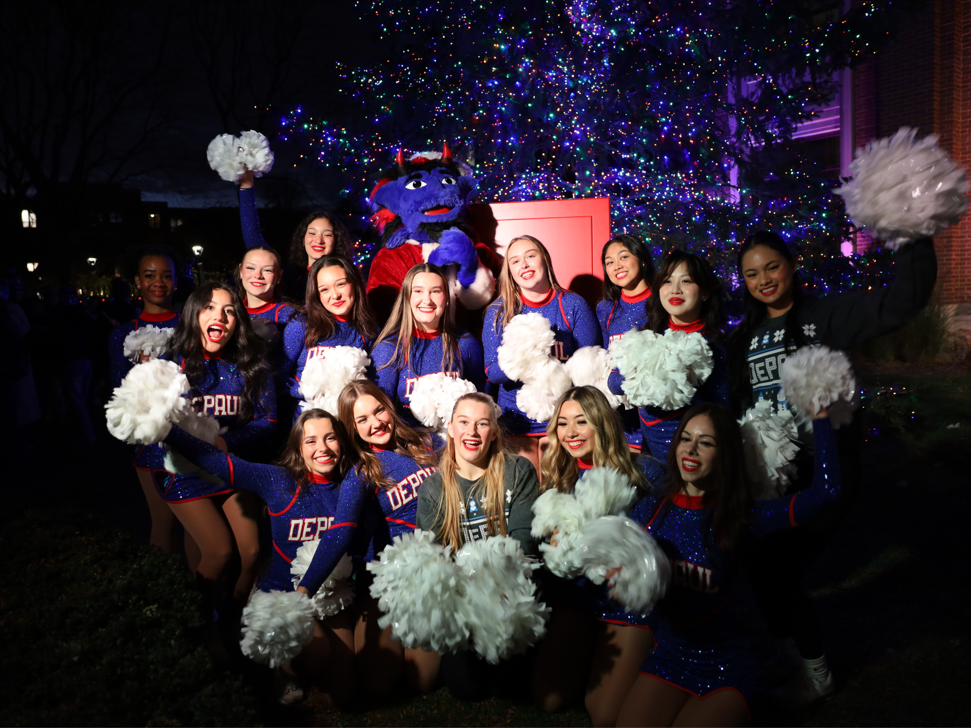 Cheer squad poses with DIBS mascot in front of a Christmas tree